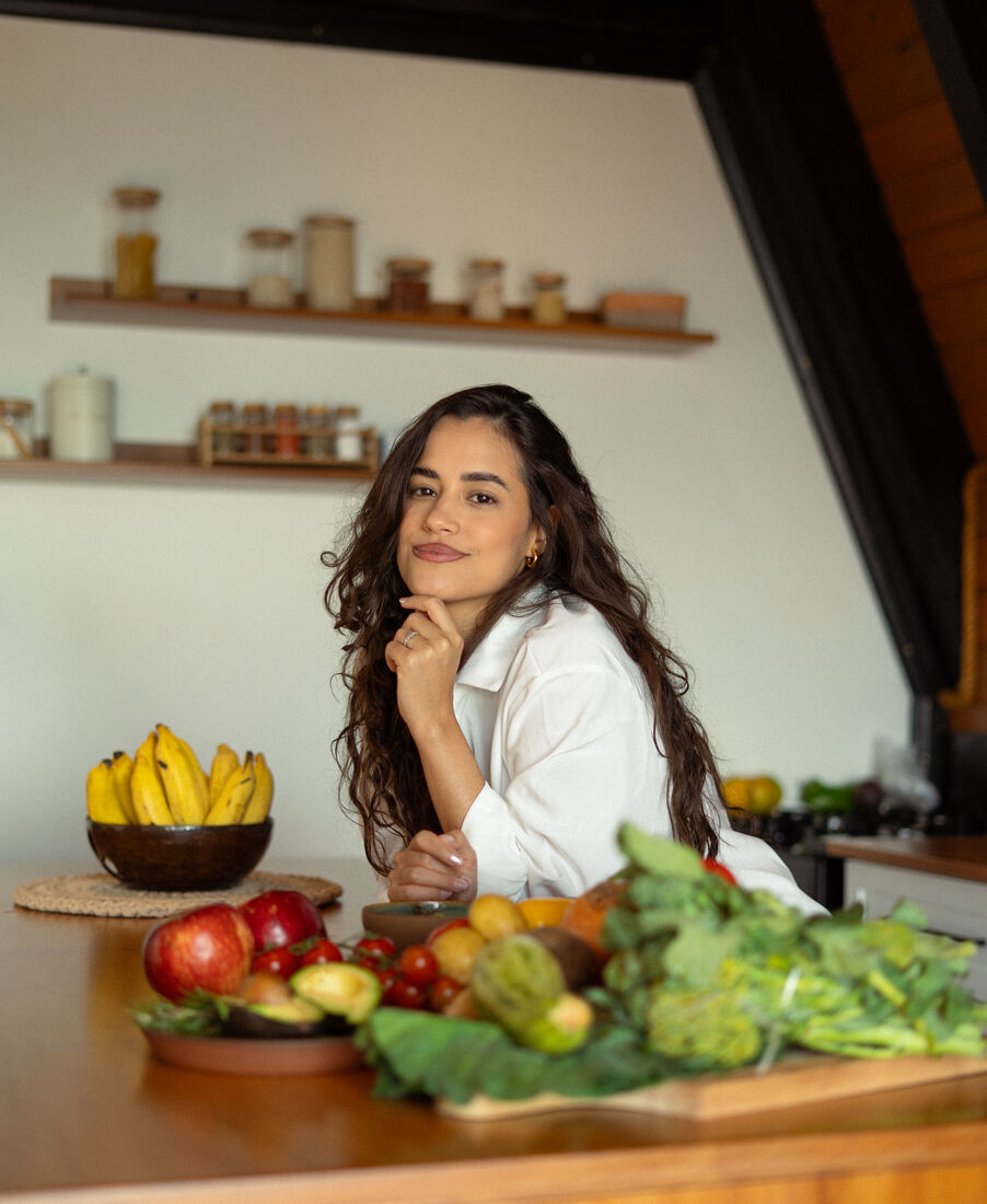 Eduarda da Luz na cozinha, cercada de frutas e verduras