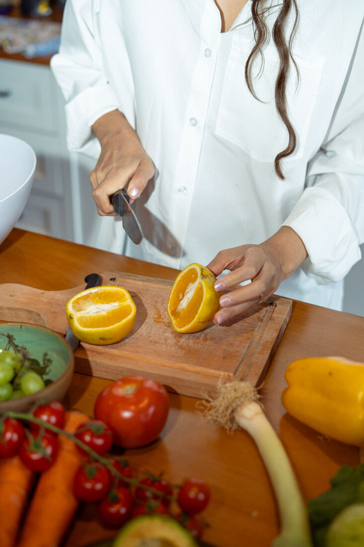 Mãos cortando uma laranja ao meio na bancada